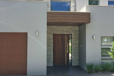 Photo of a contemporary grey house exterior in Canberra - Queanbeyan with stone veneer, a flat roof and a metal roof.