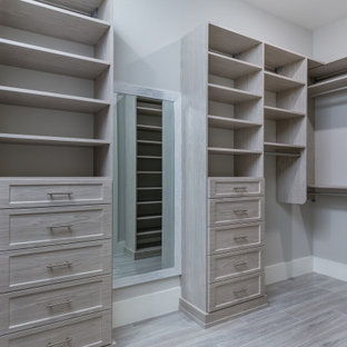 Idee per una grande cabina armadio unisex mediterranea con ante con bugna sagomata, ante in legno chiaro, pavimento con piastrelle in ceramica, pavimento grigio e soffitto ribassato