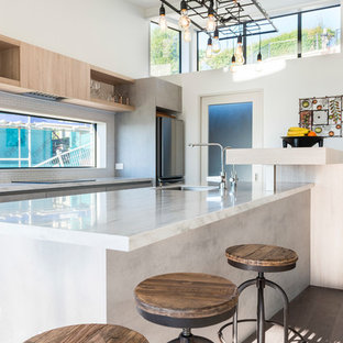 Неиссякаемый источник вдохновения для домашнего уюта: параллельная кухня среднего размера в стиле лофт с кладовкой, врезной раковиной, плоскими фасадами, серыми фасадами, столешницей из акрилового камня, белым фартуком, фартуком из плитки кабанчик, техникой из нержавеющей стали, полом из ламината, островом и бежевым полом