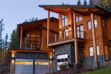 Photo of a large contemporary two-storey brown house exterior in Other with wood siding and a shed roof.