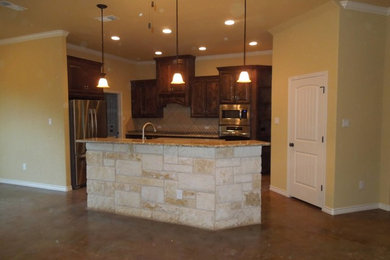 Kitchen - small traditional u-shaped kitchen idea in Dallas with raised-panel cabinets, dark wood cabinets, beige backsplash, ceramic backsplash, stainless steel appliances and an island