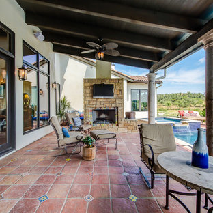 オースティンの大きいサンタフェスタイルのおしゃれな裏庭のテラス (アウトドアキッチン、タイル敷き、張り出し屋根) の写真