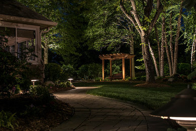 This is an example of a traditional backyard patio in Indianapolis with a water feature, concrete pavers and a pergola.