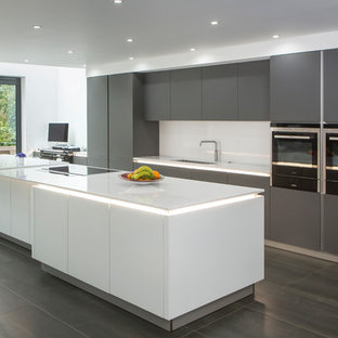Große Moderne Küche mit flächenbündigen Schrankfronten, grauen Schränken, Quarzit-Arbeitsplatte, Küchenrückwand in Weiß, Kücheninsel und Unterbauwaschbecken in Essex