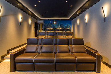 Large transitional enclosed home theatre in Los Angeles with beige walls, a projector screen and carpet.