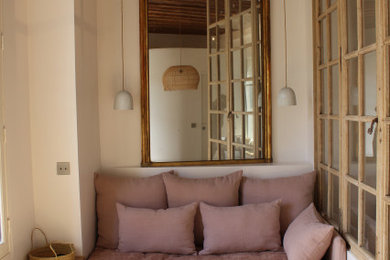 Modelo de salón abierto tradicional pequeño con paredes blancas, suelo de madera clara y vigas vistas
