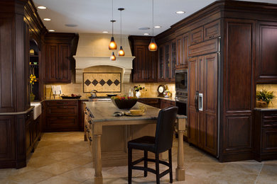 Photo of a mid-sized traditional u-shaped eat-in kitchen in Denver with a farmhouse sink, raised-panel cabinets, dark wood cabinets, beige splashback, ceramic splashback, stainless steel appliances, travertine floors, with island and granite benchtops.