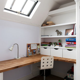 Modern inredning av ett mellanstort hemmabibliotek, med ett inbyggt skrivbord, vita väggar, heltäckningsmatta, en standard öppen spis, en spiselkrans i trä och beiget golv