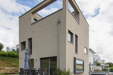 Mid-sized contemporary three-storey stucco grey house exterior in Stuttgart with a flat roof.