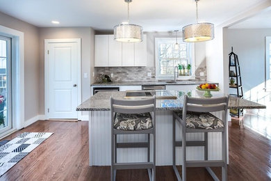 Enclosed kitchen - mid-sized transitional single-wall medium tone wood floor and brown floor enclosed kitchen idea in Other with an undermount sink, shaker cabinets, white cabinets, granite countertops, multicolored backsplash, subway tile backsplash, stainless steel appliances, an island and gray countertops
