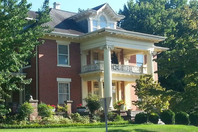 Huge traditional red three-story brick exterior home idea in Other with a hip roof