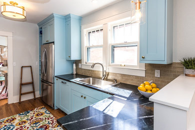 Enclosed kitchen - small craftsman galley medium tone wood floor and brown floor enclosed kitchen idea in Denver with a drop-in sink, shaker cabinets, blue cabinets, soapstone countertops, beige backsplash, porcelain backsplash, stainless steel appliances and a peninsula