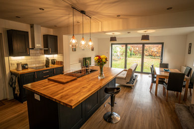 Design ideas for a large traditional kitchen/diner in Essex with wood worktops, yellow splashback, an island, brown floors and brown worktops.