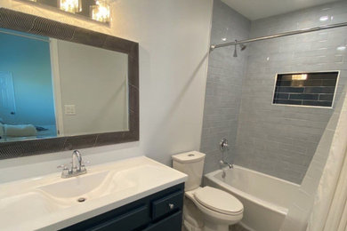 Mid-sized master gray tile and porcelain tile porcelain tile, gray floor and single-sink shower curtain photo in Los Angeles with flat-panel cabinets, white cabinets, white walls, solid surface countertops, white countertops, a niche and a built-in vanity