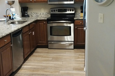 Enclosed kitchen - mid-sized traditional u-shaped light wood floor and brown floor enclosed kitchen idea in Miami with an undermount sink, raised-panel cabinets, dark wood cabinets, granite countertops, stainless steel appliances, a peninsula and gray countertops