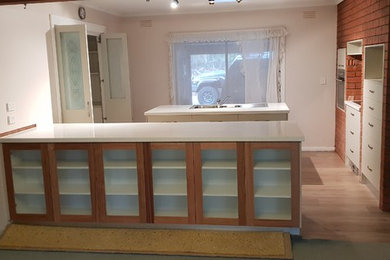 Mid-sized contemporary kitchen pantry in Other with a double-bowl sink, solid surface benchtops, with island, flat-panel cabinets and stainless steel appliances.