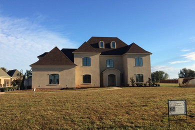 Huge traditional beige three-story stucco house exterior idea in New Orleans with a hip roof and a shingle roof