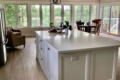 Inspiration for a contemporary l-shaped vinyl floor, beige floor and coffered ceiling eat-in kitchen remodel in Toronto with shaker cabinets, white cabinets, quartzite countertops, white backsplash, ceramic backsplash, an island, white countertops, a farmhouse sink and stainless steel appliances