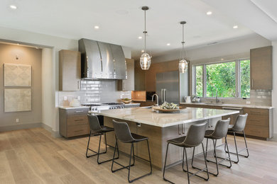 Inspiration for a contemporary kitchen in San Francisco with an undermount sink, flat-panel cabinets, light wood cabinets, white splashback, subway tile splashback, stainless steel appliances, light hardwood floors, with island and white benchtop.