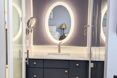 Photo of a medium sized classic ensuite bathroom in Orlando with flat-panel cabinets, blue cabinets, an alcove bath, an alcove shower, a bidet, multi-coloured tiles, ceramic tiles, purple walls, vinyl flooring, a submerged sink, quartz worktops, an open shower, white worktops, an enclosed toilet, a single sink and a built in vanity unit.