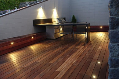 This is an example of a large modern backyard partial sun garden for summer in Christchurch with a water feature and decking.