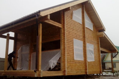 Пример оригинального дизайна: двухэтажный, деревянный, коричневый дом среднего размера с двускатной крышей