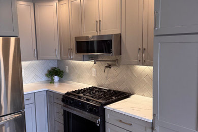 Mid-sized trendy u-shaped kitchen photo in New York with gray cabinets, gray backsplash, stainless steel appliances, a peninsula and white countertops
