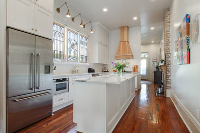 Eat-in kitchen - large transitional l-shaped medium tone wood floor and brown floor eat-in kitchen idea in New Orleans with an undermount sink, shaker cabinets, white cabinets, quartz countertops, yellow backsplash, ceramic backsplash, stainless steel appliances, an island and multicolored countertops