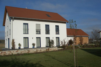 Photo of a large contemporary three-storey stucco white exterior in Munich with a gable roof.