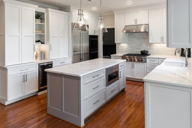 Example of a large transitional u-shaped medium tone wood floor and red floor eat-in kitchen design in DC Metro with a farmhouse sink, shaker cabinets, white cabinets, quartz countertops, white backsplash, subway tile backsplash, stainless steel appliances, an island and white countertops