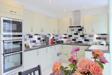 Design ideas for a medium sized contemporary l-shaped kitchen/diner in Essex with a single-bowl sink, shaker cabinets, green cabinets, multi-coloured splashback, metro tiled splashback, stainless steel appliances and no island.
