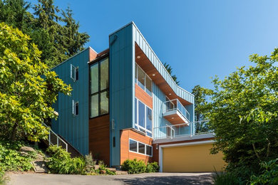 Design ideas for a contemporary three-storey blue house exterior in Seattle with mixed siding and a flat roof.