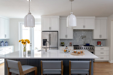 Foto di una cucina bohémian chiusa con ante bianche, paraspruzzi grigio, elettrodomestici in acciaio inossidabile, parquet chiaro, pavimento marrone e top bianco
