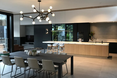 Design ideas for an expansive contemporary galley eat-in kitchen in Melbourne with an undermount sink, flat-panel cabinets, black cabinets, grey splashback, panelled appliances, porcelain floors, with island, grey floor and white benchtop.