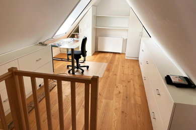 Mittelgroßes Modernes Arbeitszimmer mit Arbeitsplatz, weißer Wandfarbe, braunem Holzboden, freistehendem Schreibtisch und braunem Boden in Hannover