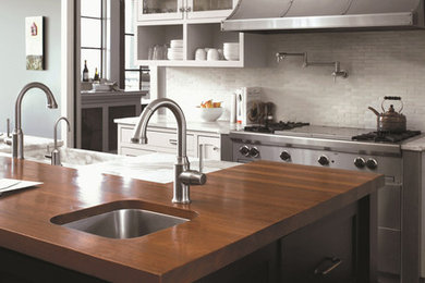 Kitchen - brown floor kitchen idea in San Diego with wood countertops, white backsplash and an island