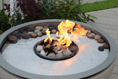 This is an example of a mid-sized contemporary backyard garden in Surrey with a fire feature.