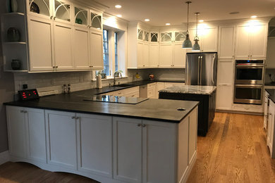This is an example of a mid-sized transitional u-shaped kitchen pantry in Bridgeport with an undermount sink, shaker cabinets, white cabinets, granite benchtops, white splashback, subway tile splashback, stainless steel appliances, medium hardwood floors, with island and brown floor.