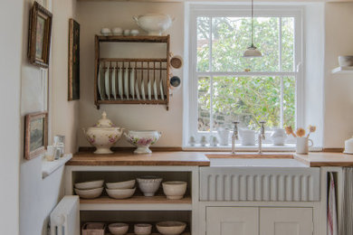 Inspiration for a small shabby-chic style single-wall kitchen/diner in London with a belfast sink, shaker cabinets, white cabinets, wood worktops, white appliances, no island, beige floors, brown worktops and a timber clad ceiling.