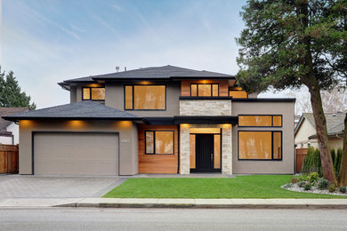 Mid-sized modern two-storey stucco beige house exterior in Vancouver with a shingle roof and a hip roof.