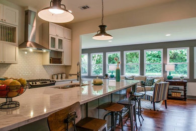 Open concept kitchen - mid-sized transitional l-shaped medium tone wood floor and brown floor open concept kitchen idea in Nashville with an undermount sink, shaker cabinets, white cabinets, quartzite countertops, white backsplash, porcelain backsplash, stainless steel appliances and an island