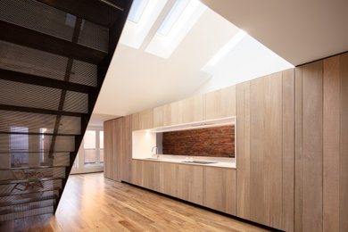 Open concept kitchen - mid-sized industrial single-wall light wood floor and yellow floor open concept kitchen idea in Other with an undermount sink, flat-panel cabinets, light wood cabinets, quartz countertops, paneled appliances, no island and white countertops