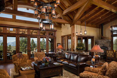 Inspiration for a large rustic formal and open concept medium tone wood floor living room remodel in Kansas City with beige walls, a corner fireplace and a stone fireplace