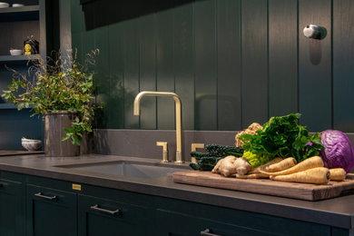 Photo of a medium sized classic kitchen in Other with a double-bowl sink, recessed-panel cabinets, green cabinets, engineered stone countertops, grey splashback, engineered quartz splashback, ceramic flooring, no island, grey floors and brown worktops.