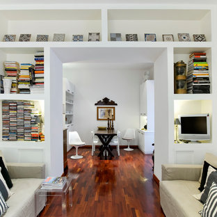 Bild på ett funkis vardagsrum, med vita väggar, mellanmörkt trägolv och en fristående TV