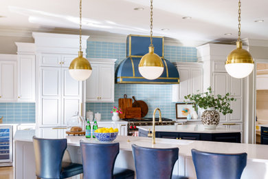 Ejemplo de cocina clásica con salpicadero azul, salpicadero de azulejos de cerámica, electrodomésticos negros, una isla y suelo beige