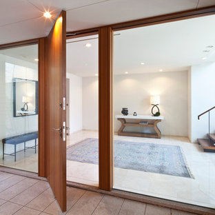 東京23区の大きい片開きドアモダンスタイルのおしゃれな玄関ラウンジ (白い壁、大理石の床、木目調のドア、ベージュの床) の写真