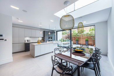 Contemporary eat-in kitchen in London with an undermount sink, flat-panel cabinets, white cabinets, white splashback, black appliances and with island.