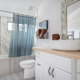 Example of a mid-sized country white tile laminate floor bathroom design in Raleigh with shaker cabinets, white cabinets, white walls, a vessel sink and wood countertops