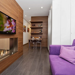 Exempel på ett mellanstort modernt allrum med öppen planlösning, med ett finrum, vita väggar, klinkergolv i porslin, en dubbelsidig öppen spis, en väggmonterad TV och brunt golv